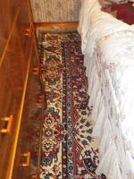 Photo showing floor placement of an 8ft x 6.9ft area rug next to furniture, revealing design and partial wear.