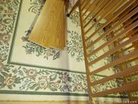 Floral patterned 7.8x11 feet area rug with border, some wear visible under wood railing