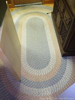 Full view of braided oval rug placed on the floor showing color pattern and condition.