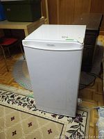 Front and side view of white Diplomat mini fridge on patterned carpets and wood flooring, showing overall condition and size.