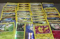 A collection of assorted Pokemon trading cards spread out showing multiple characters and foil cards, including a foil Pikachu card
