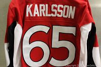 Back view of the red Ottawa Senators jersey showing player name 'Karlsson' above number 65, white and black sleeve details.