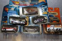Top-down photo showing all six vehicles in original packaging with significant wear and damage to cards/packaging, including bending and tears.