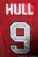 Back of red hockey jersey showing 'HULL' name and large white number '9' with Bobby Hull autograph and inscriptions