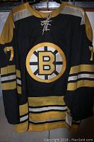 Front view of black and gold Boston Bruins jersey with Bruins logo and number 77 on sleeves.