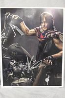 Full 8x10 photo showing Norman Reedus seated on motorcycle, autographed in silver with slight water damage.