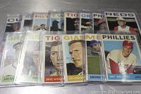 Close arrangement of the 14 assorted 1963 Topps baseball cards in protective plastic sleeves, showing fronts of all cards.