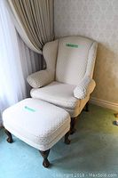 Wingback chair and ottoman set seen from front corner, showing entire pieces and upholstery detail.
