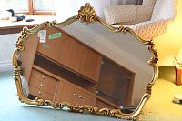 Full frontal view of gold-colored framed mirror showing ornate decorative frame and rectangular shape.