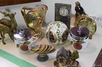 Full view of lot showing animal figurines, small clocks, ceramic ball, glass bird, sugar and creamer set, and miniature cottage sculpture.