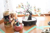Photo showing the beer stein, Fitz and Floyd pheasant container, and decorative oriental style tree on a wooden surface near lace curtains.