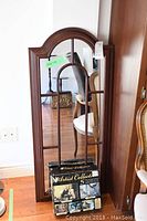 Full view of the wood framed mirror with arched top and windowpane divisions. Jigsaw puzzle set leaning against the bottom of the mirror.