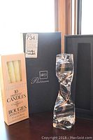 Mikasa Platinum candle holder with box of dripless candles displayed together on surface by window.