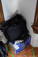 Black Sony Handycam CCD-TR5 camcorder in box with black camera bag and additional cameras placed on top, all items displayed against a white wall corner.