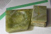 Photo shows a green jade ashtray with natural white and brown veining next to a matching rectangular jade decorative box with gold-tone accents.