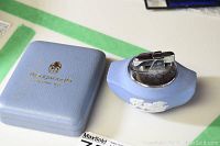 Blue Wedgwood jasperware lighter with white classical relief decoration and silver lighter mechanism, alongside original light blue box with gold Wedgwood logo.