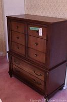 Front and side view of a wooden chest of drawers showing six smaller upper drawers with wooden knobs and two larger bottom drawers with metal handles.