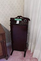 Front view of dark wood clothes butler with hanger and base visible