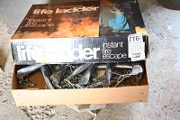 Partially opened box showing the folded fire escape ladder inside with metal segments and hooks.