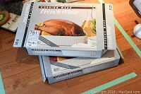 Two boxed Corning Ware French White open roasters each listed as 4.5 L capacity, stacked on a wooden table.