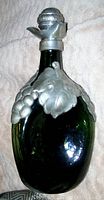 Green pinched art glass liquor decanter with raised pewter grape and leaf design covering the shoulders and neck. Cork pewter stopper attached.