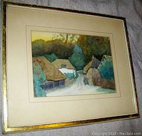 Frontal view of the matted and framed painting leaning at an angle on fabric background