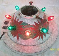 Front view showing five light bulbs illuminated, red floral patterns, and textured gray stand surface.