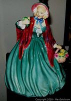 Front view of Royal Doulton Lady Charmian figurine, showing full dress and holding basket of flowers and bird.