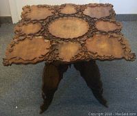 Front top view showing carved wooden square table top with ornate leaf and scroll motifs and central oval design