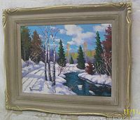 Framed oil painting showing a snowy forest scene with a stream and birch trees, signed R. MacDonald, angled view.