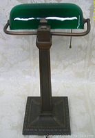 Front view of lamp showing green glass shade and square metal base