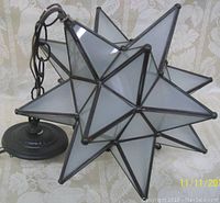 Close-up image of star-shaped frosted glass panels with metal framing, showing the geometric design of the fixture.