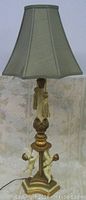 Full lamp with fabric lampshade and cherub figures on the base.