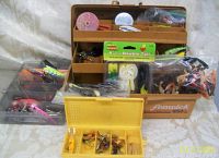 Overview of Fenwick 1050 electronic tackle box open with various lures, weights, hooks and fishing accessories visible inside compartments and smaller yellow box in front.