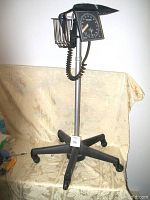 Full view of the Welch Allyn blood pressure monitor mounted on a wheeled metal stand, showing the height and basket.