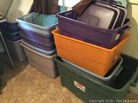 Stack of 14 assorted plastic storage bins in various colors with lids included