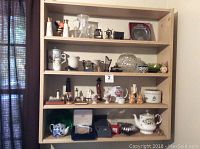 Photo of multiple shelves displaying a wide variety of collectible small figurines, ceramic items, glassware, and souvenir items. Shelf not included.