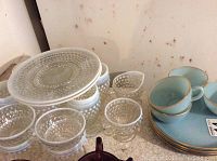 Blue hobnail sherbet and water glasses, open sugar bowl and creamer, and blue Fire King luncheon plates.