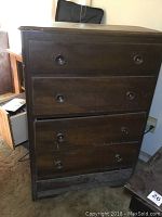 Front view showing four wooden drawers with round knobs and visible wear on the surface.