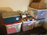 Overview of multiple plastic bins stacked and arranged, containing Christmas decorations and Hallmark Keepsake ornaments.