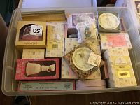 Top view of plastic storage bin filled with boxed Precious Moments figurines and collectibles, showing multiple original boxes with floral and pastel decoration.