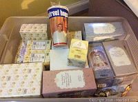 Overview photo showing multiple boxes of Precious Moments figurines in a clear storage bin, including a Street Boys cup visible on top.