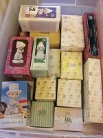 Overhead view of plastic bin filled with boxed Precious Moments figurines in various designs and colors