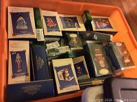 Plastic bin filled with over 30 Hallmark Keepsake Ornaments in original boxes showing various designs including Barbie themed and other holiday figures.