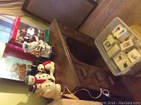 Photo of snowmen and dog figurines on dresser with cookie jar in background.