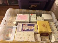 Plastic bin filled with multiple Precious Moments figurine boxes, showing variety of box designs and condition typical for collectible items.