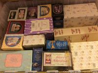 Multiple boxed Precious Moments figurines stacked in a container, showing variety of colors and box designs.