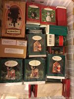 Plastic bin containing approximately 30 Hallmark Keepsake Ornaments in original boxes, arranged in rows with visible green collector's club boxes and other colored boxes including brown and red.