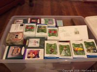 Clear plastic bin containing multiple Hallmark Keepsake Ornaments in their original boxes arranged inside.