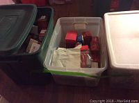 Three plastic storage bins: green and clear containers filled with red and white Hallmark Keepsake ornament boxes